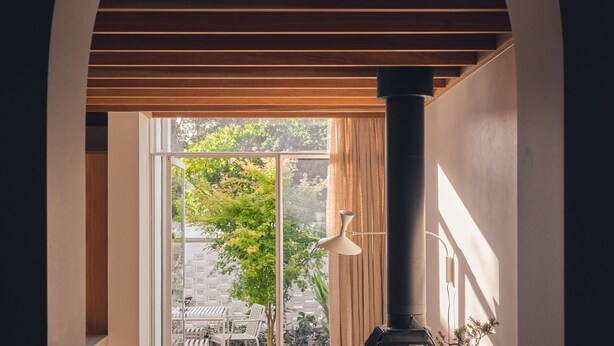 A modern interior with a large window, a black column, and a white pendant light.