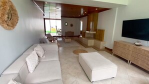 A modern living room with a sectional sofa, ottoman, and a flat-screen TV. - Spacious 5BR in Escazu w/Jacuzzi, Sauna & Fire Pit (San Rafael)