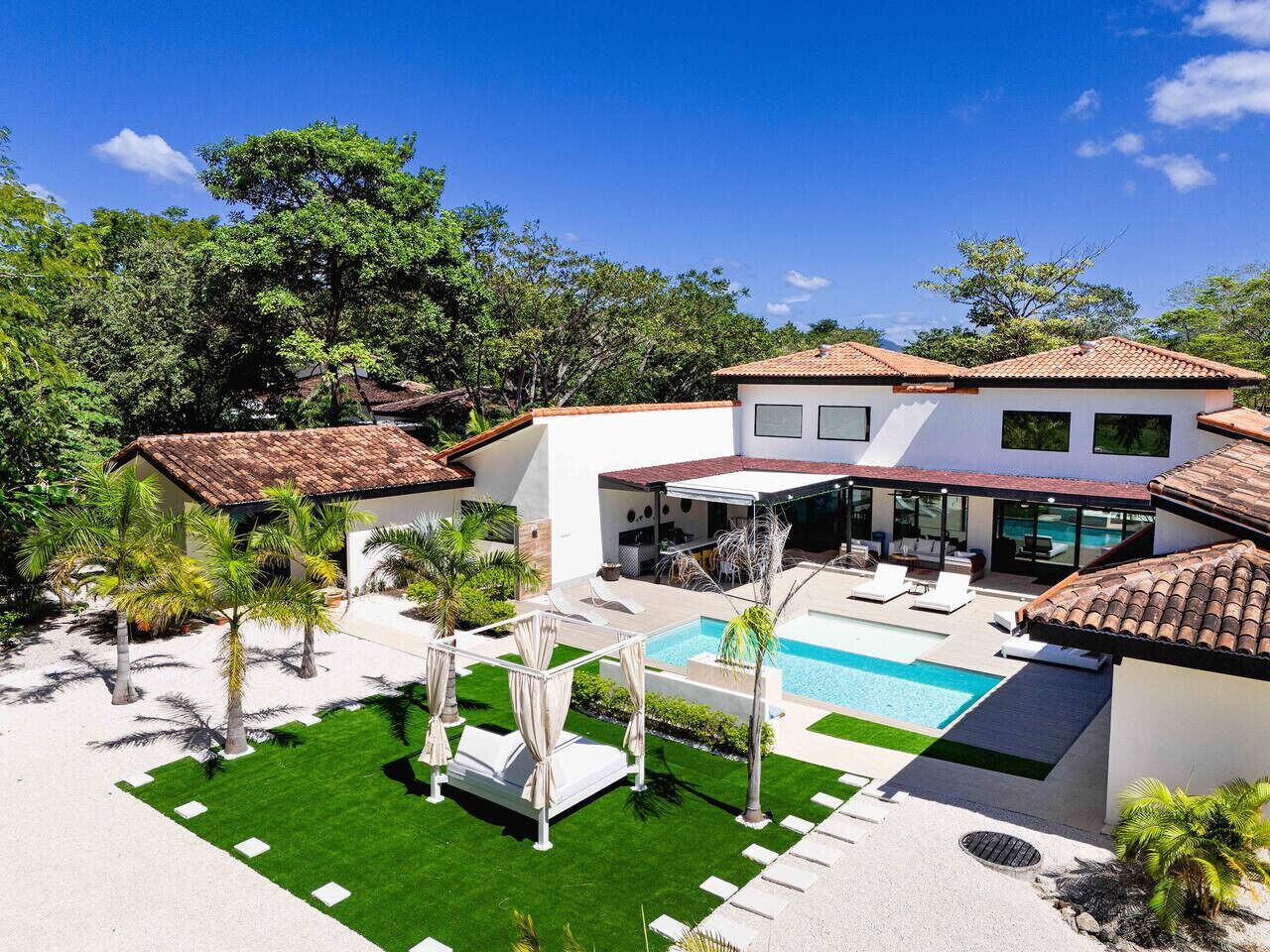 Une maison moderne dotée d’une piscine, d’un espace salon extérieur et d’une végétation luxuriante.