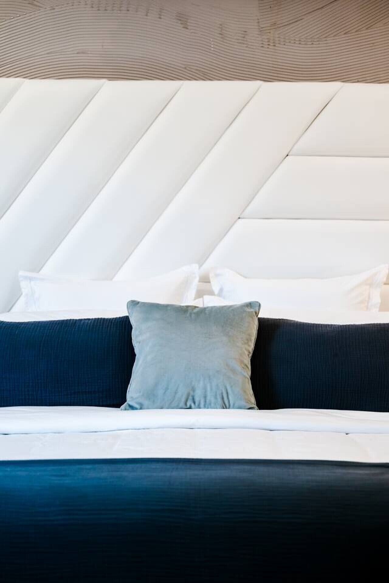 A bed with a white headboard, two pillows, and a dark blue mattress.