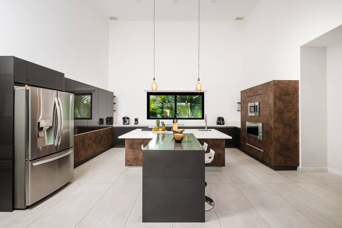 A modern kitchen with a central island, stainless steel appliances, and a large flat-screen TV.