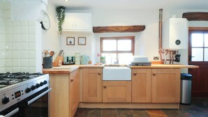 A kitchen with wooden cabinets, a gas stove, a sink, and a window. - Sunnybrook Cottage (Lancaster)