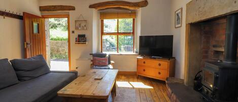 A cozy living room with a sofa, a wooden table, a television, and a fireplace.