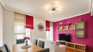 A modern living room with a dining area, a flat-screen TV, and a wooden floor. - Charming apartment in Castro (Castro-Urdiales)