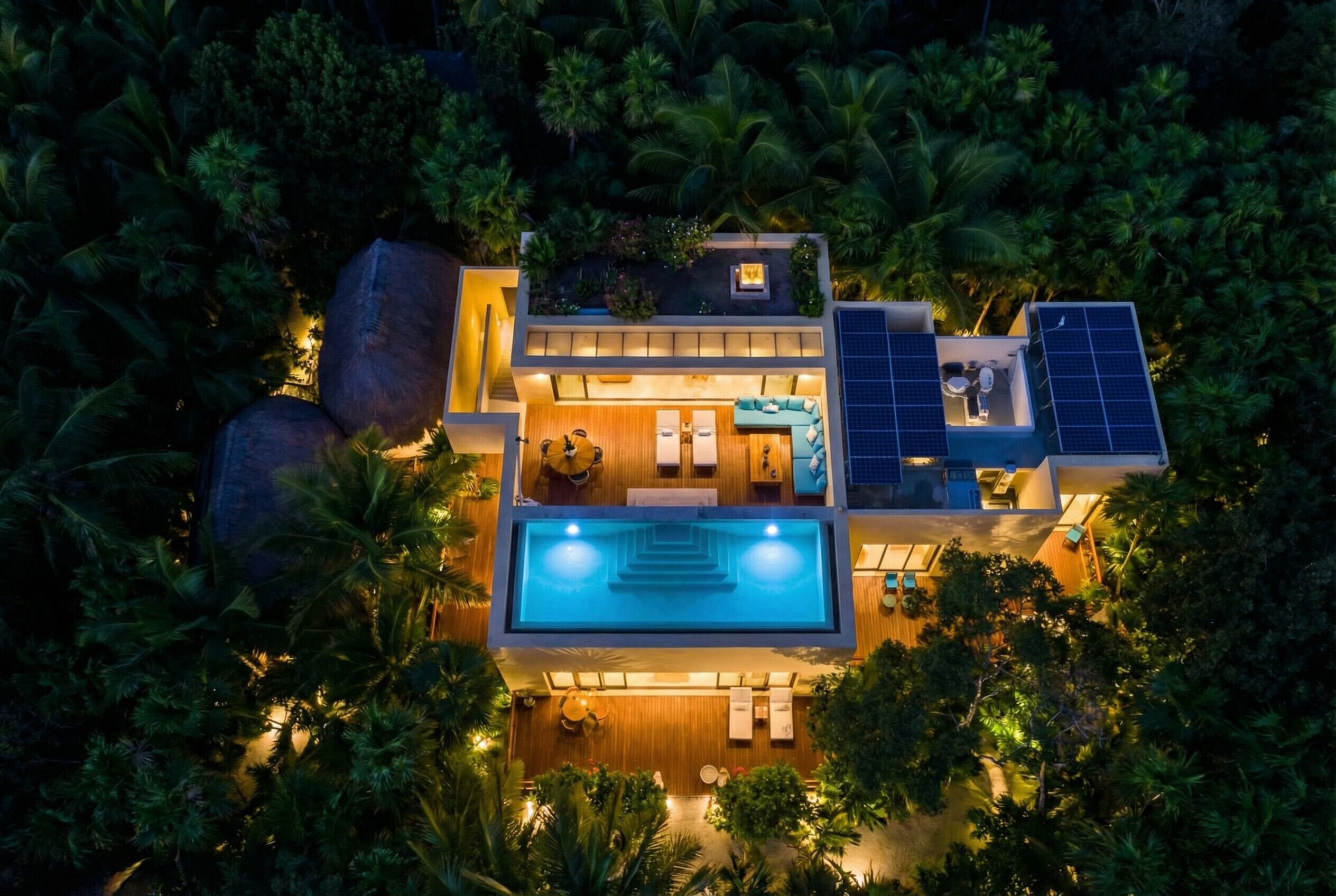 Una casa moderna con piscina, pannelli solari e un lussureggiante ambiente tropicale.