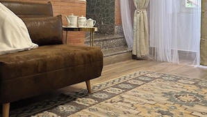 A cozy room with a brown sofa, a small table with tea sets, a patterned rug, a stone accent wall, and sheer curtains. - Elegant holiday home situated in Salerno, city centre, a few km from Amalficoast (Salerno)