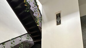 A living room with a brown sofa, a patterned rug, a small table with a tea set, a staircase with a black railing, and a wall with a stone pattern. - Elegant holiday home situated in Salerno, city centre, a few km from Amalficoast (Salerno)