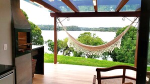 Una hamaca bajo una pérgola con vistas a un lago y follaje.