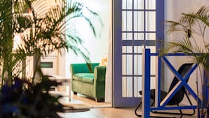 Une pièce avec un canapé vert, une porte bleue et une porte dotée d’une fenêtre.