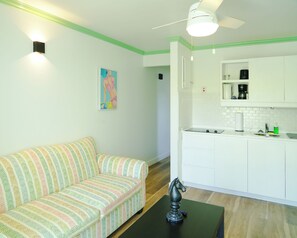 A modern kitchen with white cabinets, a black countertop, and a small sink. - Sunset Lane Apartment Hotel (Holetown)