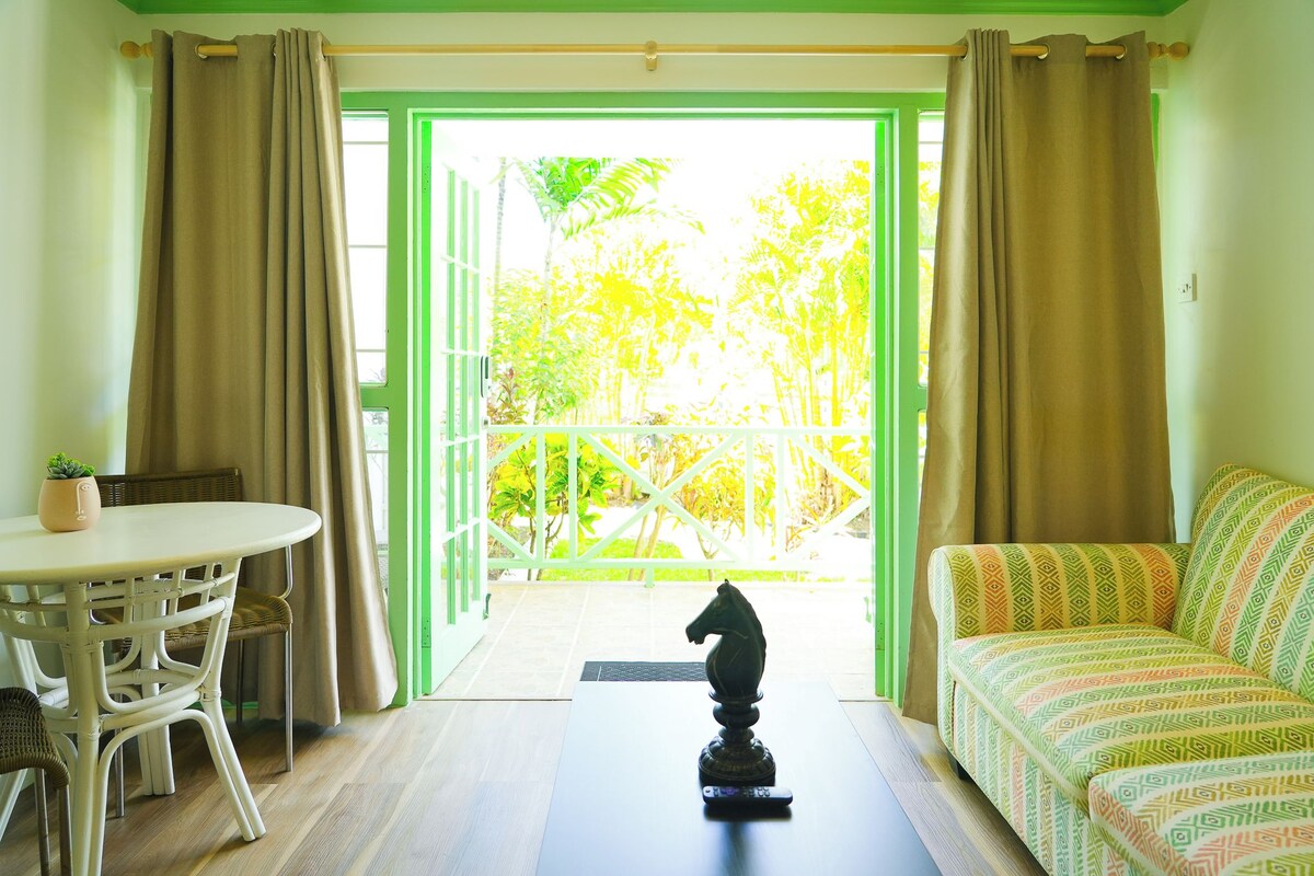 A room with a balcony, a sofa, a table, and a decorative horse statue.