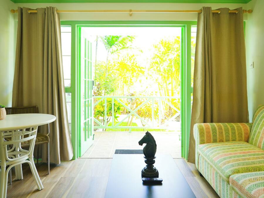 Una habitación con balcón, un sofá, una mesa y una estatua decorativa de un caballo.