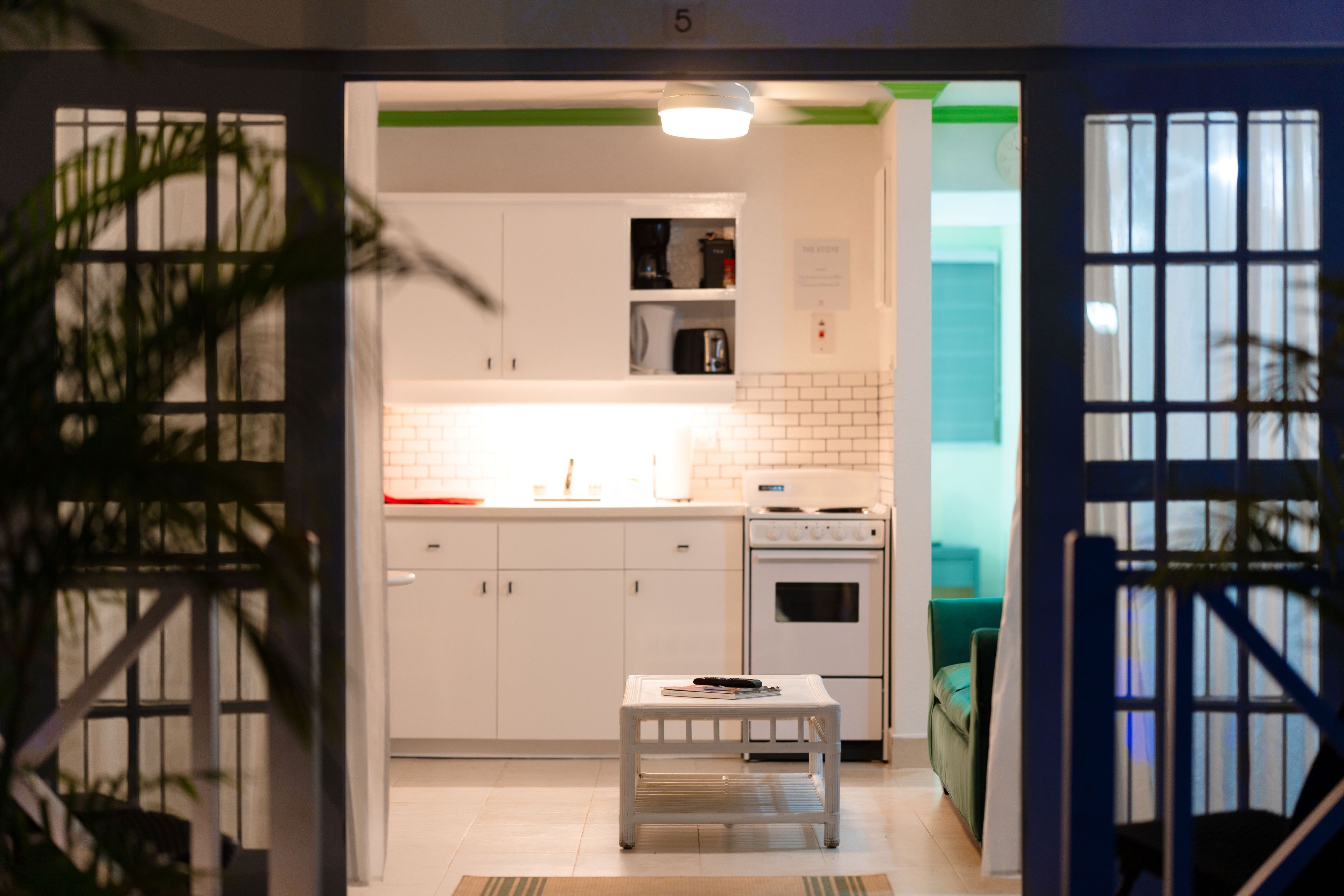 A modern kitchen with white cabinets, a built-in oven, and a small table with a remote control.