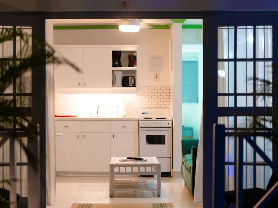 Una cocina moderna con armarios blancos, horno integrado y una pequeña mesa con un control remoto.