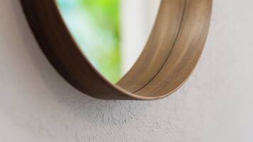 A curved mirror with a wooden frame mounted on a textured wall.