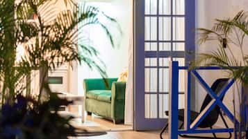 A room with a green sofa, a blue gate, and a door with a window.