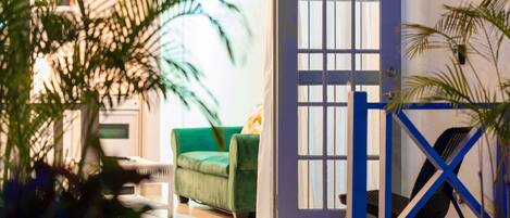 A room with a green sofa, a blue gate, and a door with a window.