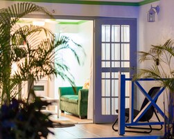 Una habitación con un sofá verde, un portón azul y una puerta con ventanal.