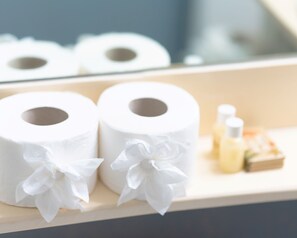 Kaksi koristeltua wc-paperirullaa, pieni pullo ja laatikko puisella alustalla.