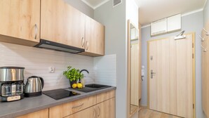 Eine moderne Küche mit Holzausbau, einer Edelstahl-Kaffeemaschine, einem Spülbecken und einem Blumentopf.