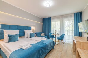 A modern hotel room with a large bed, a desk, and a chair.