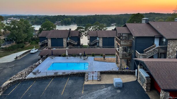 Un hotel con piscina, varias habitaciones e vista a un lago al atardecer.