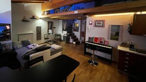 A cozy living room with a sofa, a coffee table, and a piano. There is a staircase leading to an upper level. - Apartment in the heart of the Valtellina, in an 18th century farmhouse. (Morbegno)