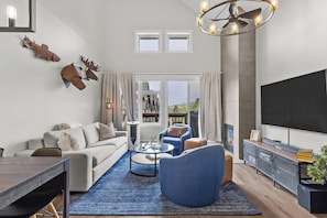A modern living room with a sofa, armchairs, a coffee table, a TV, and a fireplace.