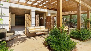 A covered outdoor seating area with wooden beams, a sofa, and a table. - Redfish Village M2321- Changes in Latitude (Santa Rosa Beach)