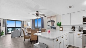 A modern hotel room with a dining area, kitchen, and balcony with a view. - Sundestin 1818 (Destin)