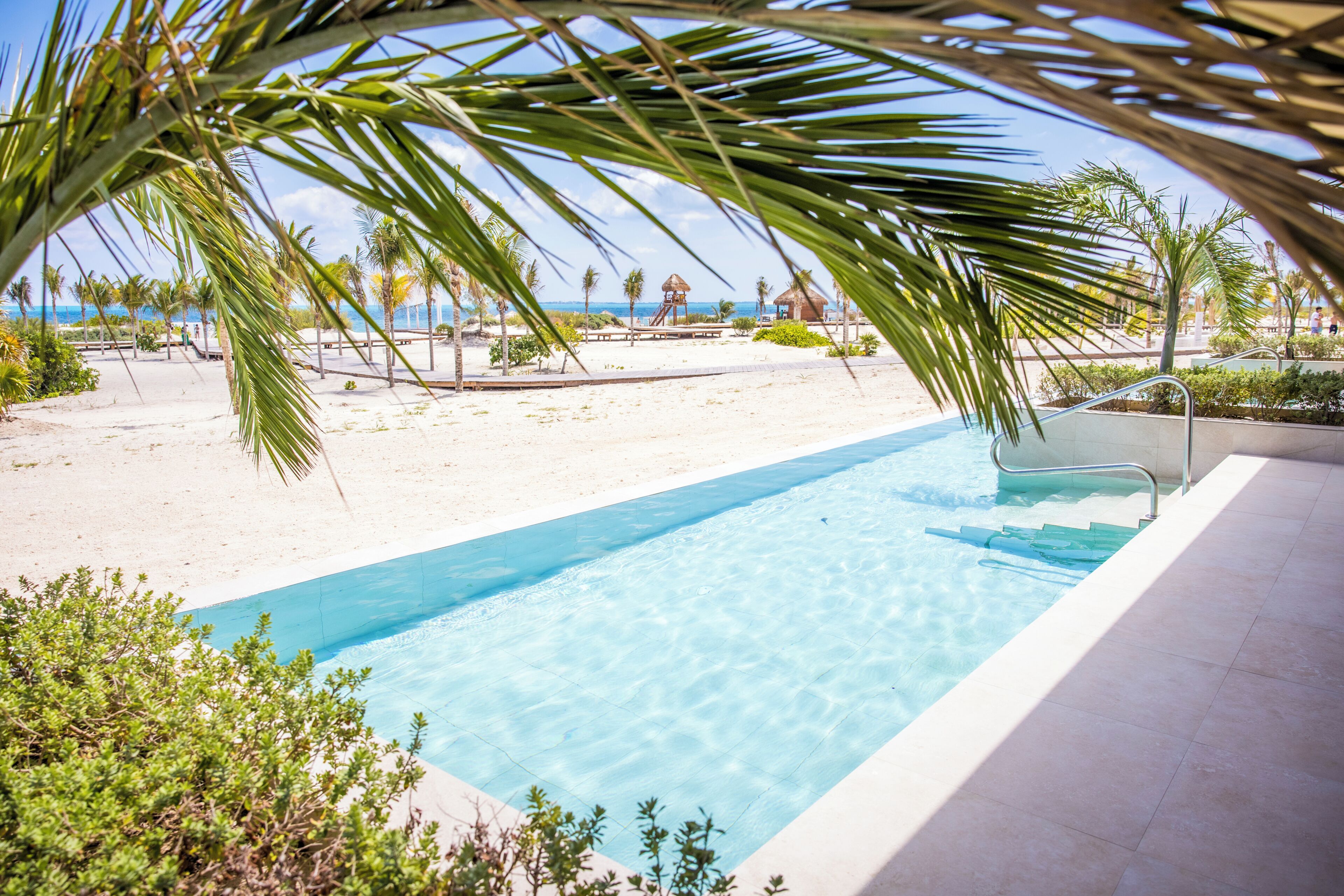 A clear blue pool with a view of the beach and ocean.