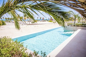 Une piscine d’eau cristalline offrant une vue sur la plage et l’océan.