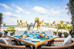 Una mesa lista para comer con vista a la playa y al océano.