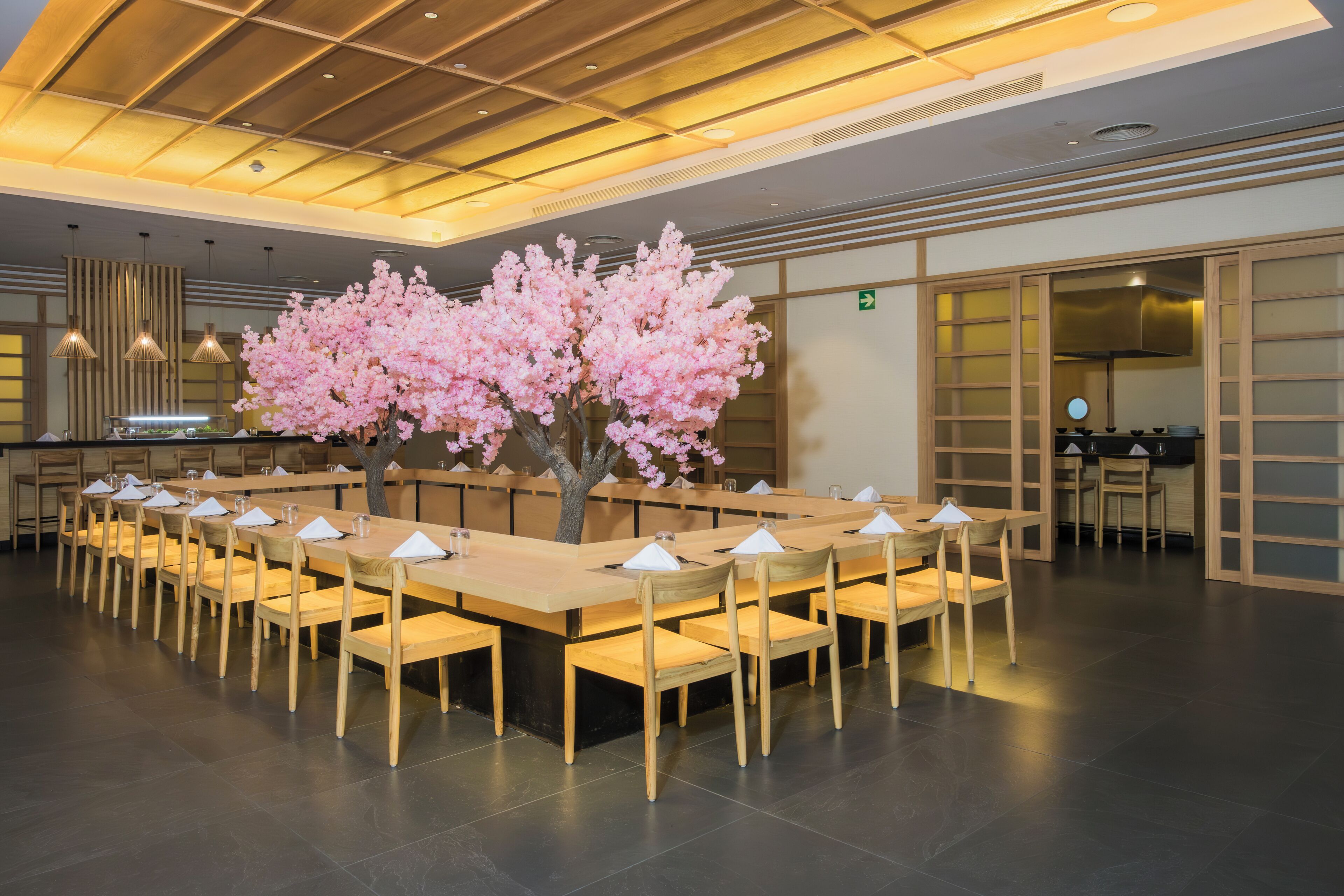A long dining table with chairs, a central floral arrangement, and a modern ceiling design.