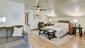 A cozy bedroom with a bed, a desk, a chair, and a sofa.