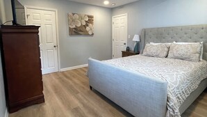 Un dormitorio con una cama grande, suelo de madera y techo con vigas a la vista.