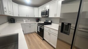 Una cocina moderna con armarios blancos, electrodomésticos de acero inoxidable y piso de madera.