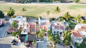 Vista aérea de una zona residencial con casas, palmeras y una carretera.