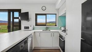 Une cuisine moderne équipée d’un lave-vaisselle, d’un four à micro-ondes, d’un évier et d’une fenêtre donnant sur la campagne.