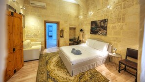 A bedroom with a large bed, a wooden wardrobe, a small table with a lamp, and a chair. - Magestic palazzo, jacuzzi on roof terrace GOVAL-3 (Valletta)