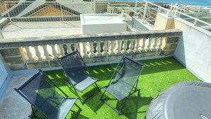 A rooftop terrace with artificial grass, two sun loungers, and a view of the sea and cityscape. - Magestic palazzo, jacuzzi on roof terrace GOVAL-3 (Valletta)