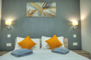 Habitación de hotel con una cama, dos lámparas de pared, un cuadro y dos enchufes.