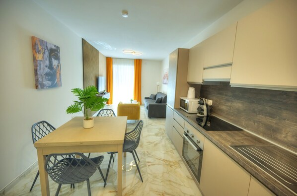 Una cocina moderna con encimera de mármol, un comedor con mesa y sillas, y una sala de estar con sofá y cortinas.