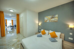 Een hotelkamer met een bed, twee bedlampen, een schilderij aan de muur en uitzicht op de gang.