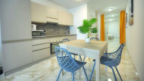 A modern kitchen with white cabinets, a marble countertop, and a dining area with a table and chairs. - Cosy & modern apartment in Paceville CPAC2-1 (St Julian's)