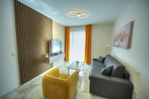 Una sala moderna con un sofá, un sillón amarillo, un televisor y un cuadro en la pared.
