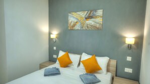 A hotel room with a bed, two nightstands, two wall-mounted lamps, and a painting on the wall. - Cosy & modern apartment in Paceville CPAC2-1 (St Julian's)