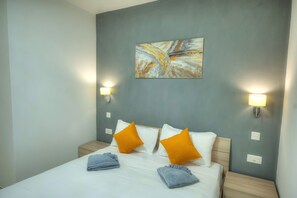 Een hotelkamer met een bed, twee nachtkastjes, twee wandlampen en een schilderij aan de muur.