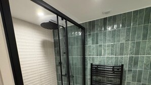Une salle de bain moderne avec une douche à parois de verre, des murs carrelés et un porte-serviettes noir.