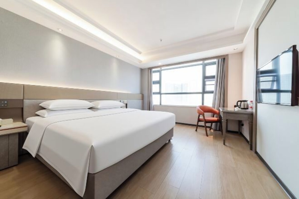 A modern hotel room with a large bed, a desk, and a chair.